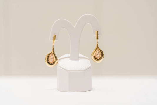 a pair of gold and diamond earrings on a white stand